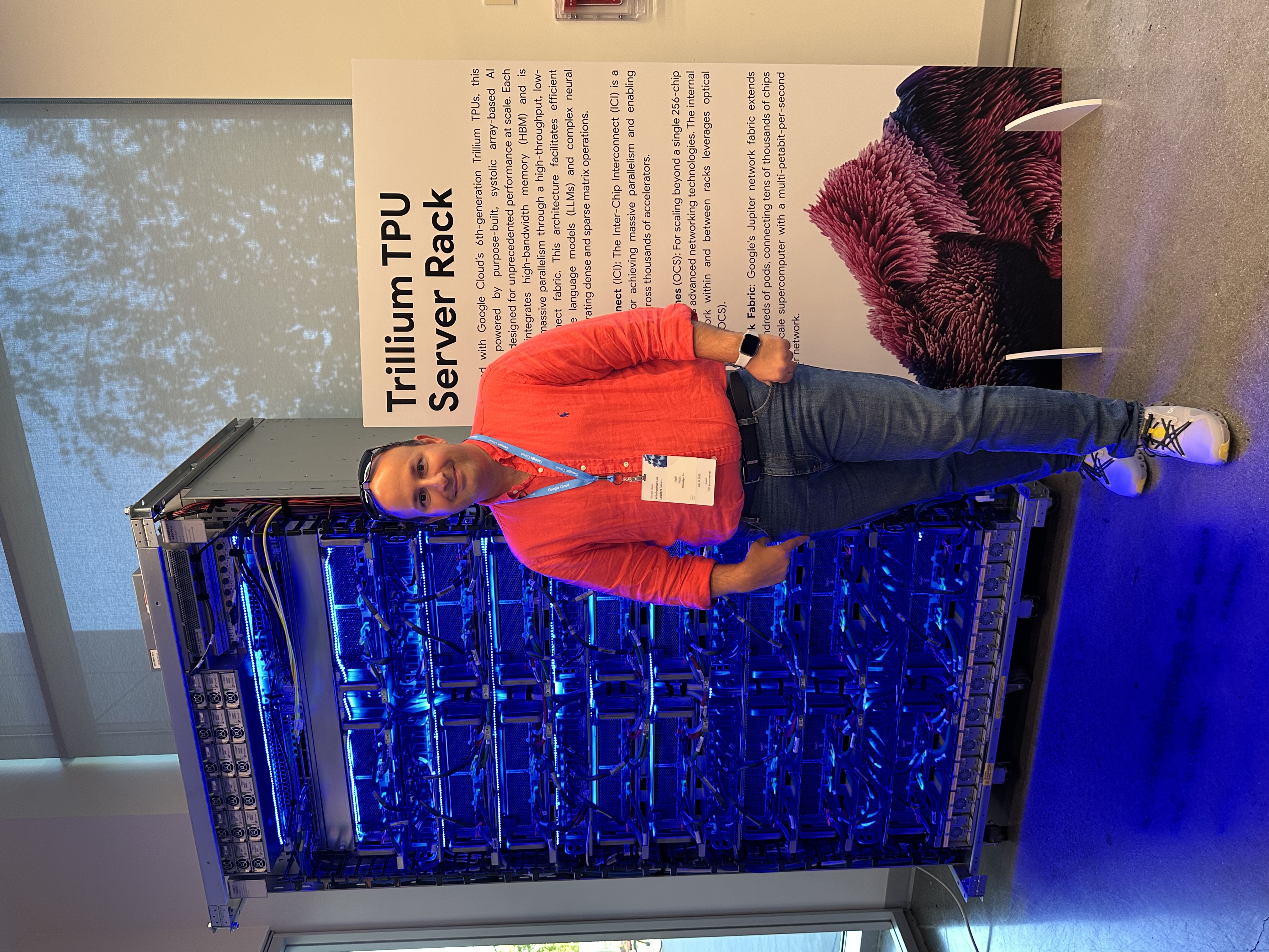 Hadi Nejati standing beside a Trillium TPU server rack.